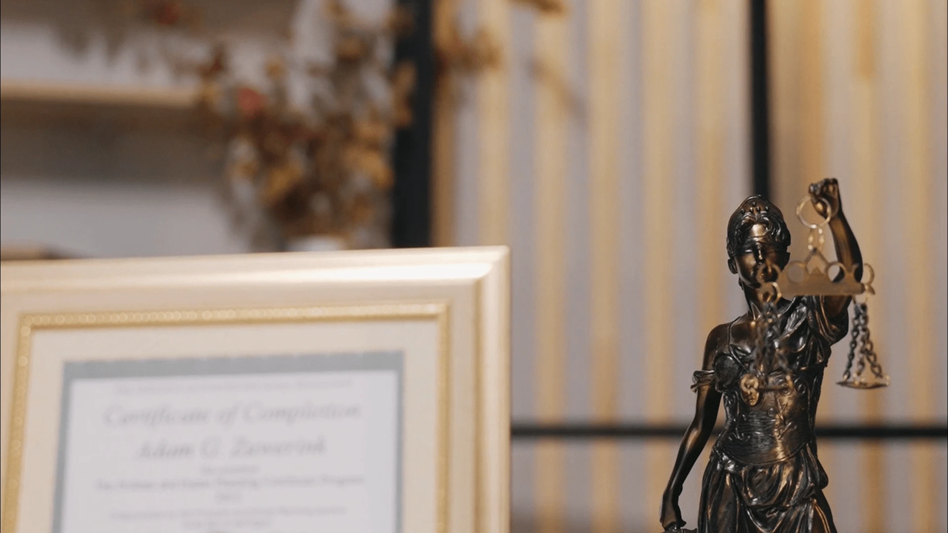 female figurine holding a scale and a certificate on a frame